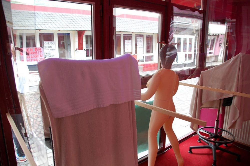 Ausblick auf die Herbertstraße, zwischen den Stühlen der Frauen ist ein Platz durch eine Gummipuppe ersetzt, damit der Abstand während Corona gewahrt bleibt.