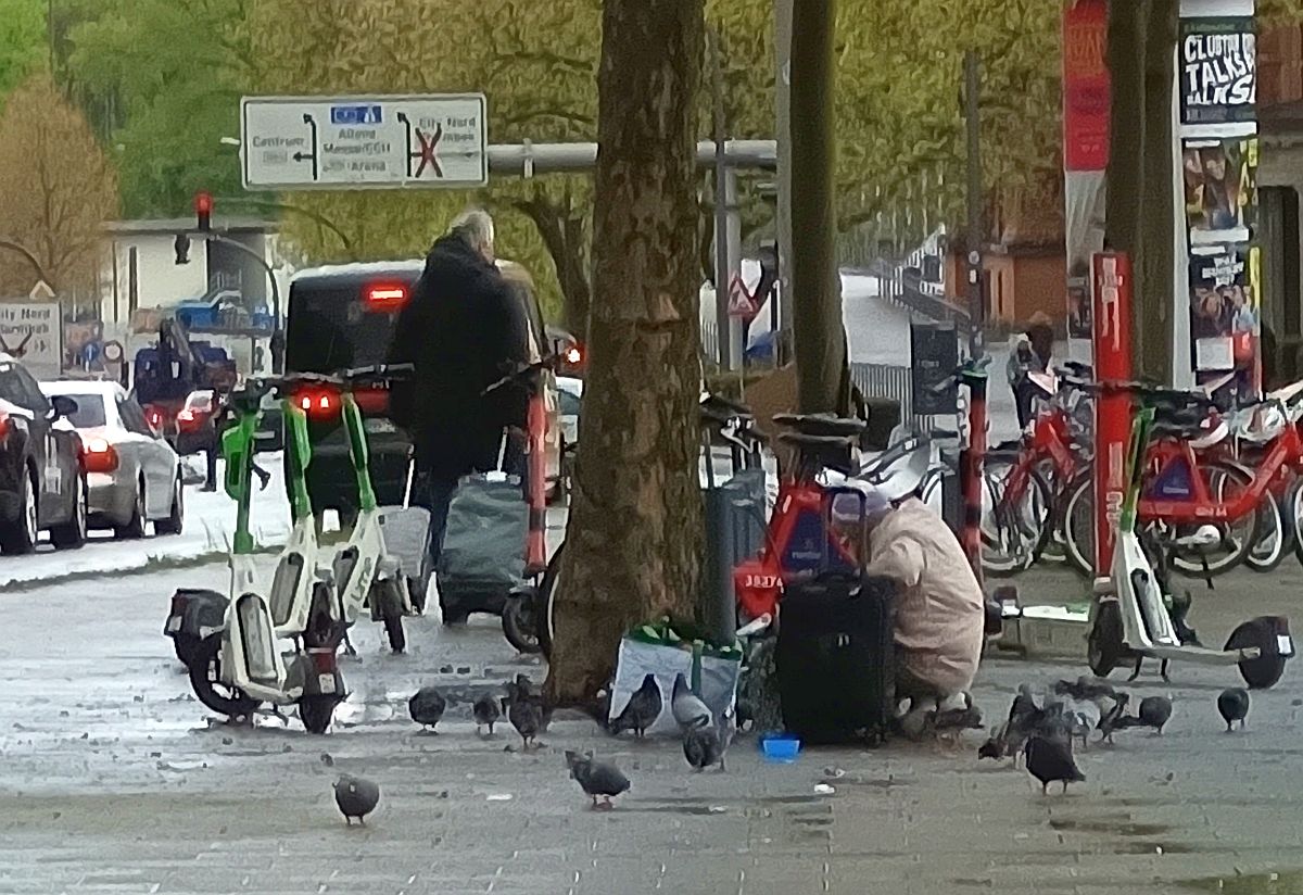Frau, die Tauben mit Wasser versorgt, am Hamburger Hauptbahnhof.