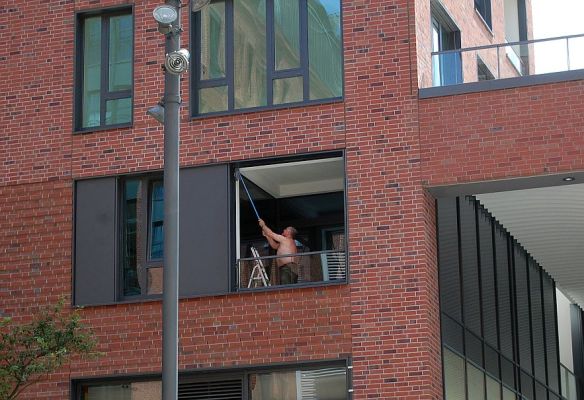 Mann beim Fensterputzen an einem h.eißen Tag in Hamburg.