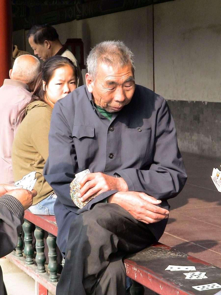 Chinesen lieben das Kartenspiel. Alter Mann mit Karten beim Himmelstempel.